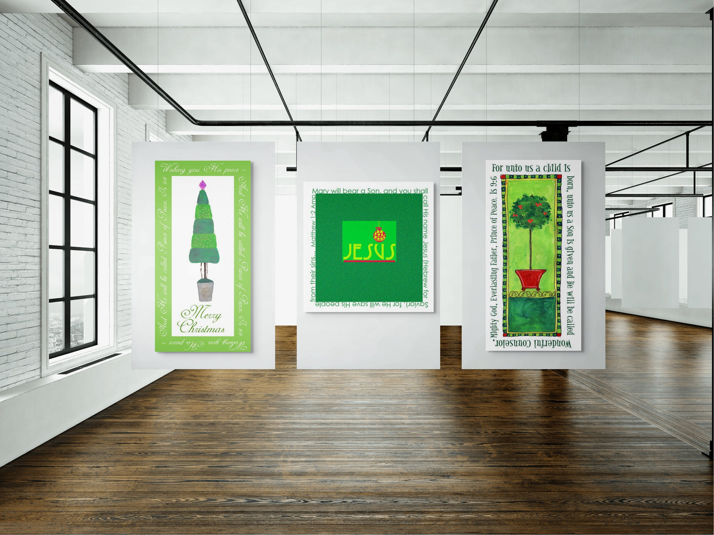 Three Christmas artworks on a white wall in a room with wooden flooring and large windows.